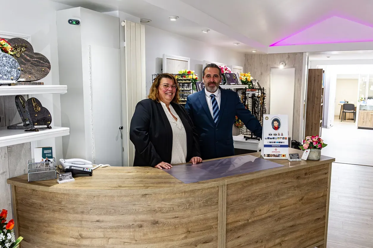 Équipe de conseillers funéraires accueillant les familles au comptoir d'agence.