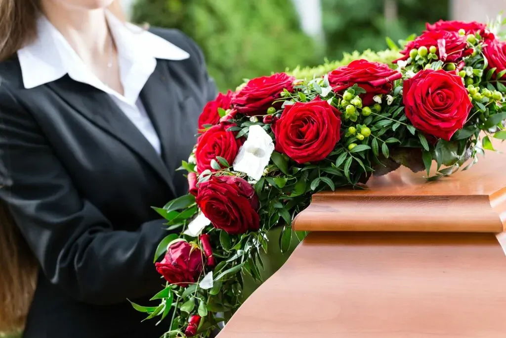 Arrangement floral de roses rouges posé avec soin sur un cercueil en bois.