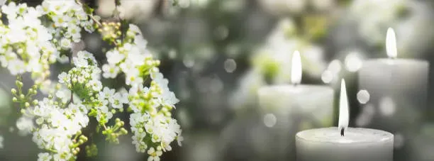 Bougies blanches allumées et fleurs blanches pour un hommage poétique.