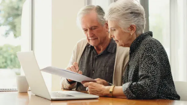 Couple de seniors remplissant un contrat de prévoyance funéraire à domicile.